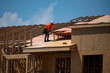 © Volodymyr - Roofing construction. Roofer roofing on roof structure. Roofing Wooden House Frame. Worker roofer builder working on roof at construction site. Construction builders Roofing.