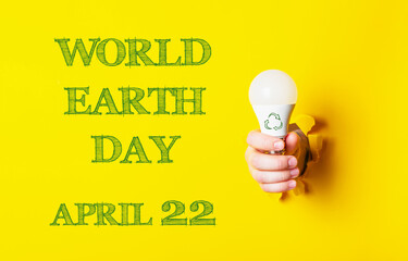 Wall Mural - A person holding a light bulb with the words World Earth Day on the background