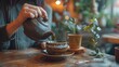 © pitu - A woman carefully pours hot tea into a cup placed on a wooden table