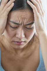 Wall Mural - Face of Asian woman suffering from headache migraine pain. Female holds head with hand
