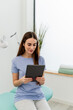© nomad studio/Stocksy - Young woman browsing tablet in modern medical office