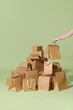 © Marc Tran/Stocksy - A hand hold paper bag near multiple parcel boxes on green background