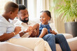 © peopleimages.com - Black family, child and people on lounge, love and happy together at home for happiness. Kid, mother or father inside bonding with girl for embrace, support or caring parents for hug in apartment