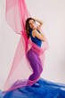 © Tania Cervian/Stocksy - Charming dancer draped in pink and blue fabrics looking at camera