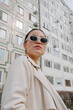 © Azamat Mukanov/Stocksy - Woman in sunglasses against the background of an apartment building