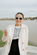 © Azamat Mukanov/Stocksy - Asian woman in sunglasses with coffee