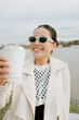 © Azamat Mukanov/Stocksy - Asian woman in sunglasses with coffee