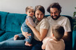 © Lea Jones/Stocksy - happy family with baby girl and little boy hugging on sofa