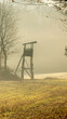 © Wirestock - Vertical shot of a silhouette of an observation tower in a misty field with trees