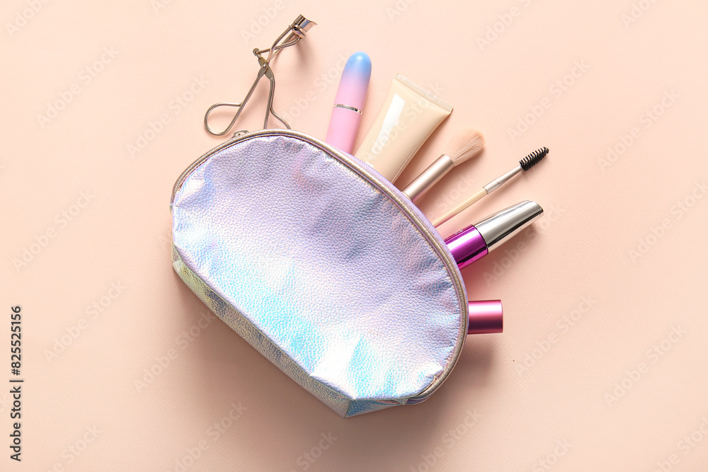 Shiny cosmetic bag with makeup products and accessories on beige background