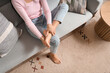 © Pixel-Shot - Woman making foot massage on sofa at home