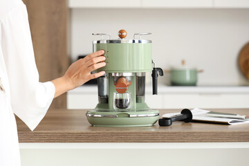 Sticker - Beautiful young woman making espresso with modern coffee machine in kitchen, closeup