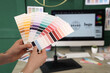 © Pixel-Shot - Young female graphic designer with color palettes in office, closeup