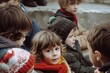© Enrique - Group of children in winter clothes sitting on the ground and looking at camera