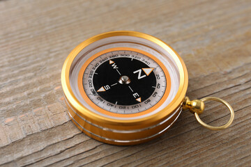 One compass on wooden table, closeup. Navigation equipment