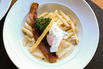 Wall Mural - Penne carbonara creamy with bacon and fresh egg in white plate, Italian food. Delicious Italian pasta. 