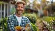 © Алина Бузунова - happy caucasian man holding shears and pruners, standing in the garden with green trees and bushes at sunny summer day.