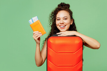 Wall Mural - Traveler fun happy woman wear yellow casual clothes hold bag passport ticket isolated on plain green background. Tourist travel abroad in free spare time rest getaway. Air flight trip journey concept.