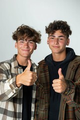 Wall Mural - Brothers posing with thumbs up against a neutral background