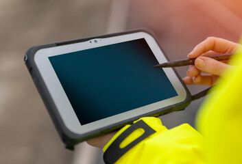 hands of site engineer surveyor using rugged tablet controller computer to operate EDM total station 