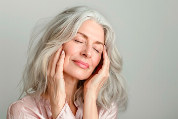 Wall Mural - A woman with gray hair is smiling and resting her head on her hand