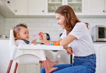 Canvas Print - Happy mother, kitchen and feeding baby with spoon on high chair for meal, snack time or breakfast at home. Mom with infant, newborn or child for food, nutrition or care with love or support at house