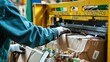 © Justlight - Closeup of a worker operating a baler machine compacting cardboard boxes for more efficient recycling.