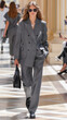 © MagicsPhotos - person walks down a runway in a black suit with an oversized blazer and trousers, featuring large pockets and a high-fashion design