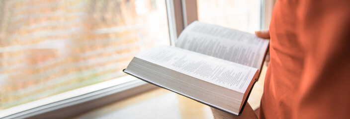 Wall Mural - Man reading bible near window, spiritual concept, stock photo