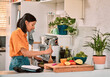 © peopleimages.com - Cooking, food and recipe with woman in kitchen of home for preparation of diet, health or nutrition. Ingredients, stove and vegetables with person making dinner in apartment for hunger or meal