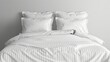 © Viktoriia Kan - A white bed with striped satin linens, several pillows and pillowcases of the same color. The background is a regular wall.