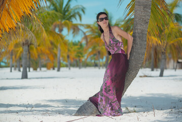 a girl in a dress and hat walks along the white sand among palm trees, dance siren in Cuba, Caribbean sea, palm trees on the beach