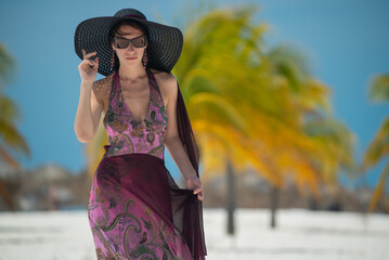 a girl in a dress and hat walks along the white sand among palm trees, dance siren in Cuba, Caribbean sea, palm trees on the beach