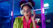 © peopleimages.com - Woman, night and headphones for music, glasses and dancing for motivation in office. Happy female person, hip hop playlist and movement in neon light, connection and streaming radio while working