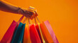 © Kalana - hand holding shopping bags , orange copy space background to make empty advertising banner for a sale , shopping banners