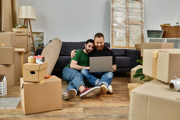Wall Mural - A man and a woman sit on the floor surrounded by boxes, focused on a laptop screen together.