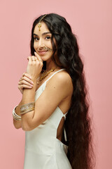 A beautiful indian woman with long hair striking a pose on a vibrant pink background.