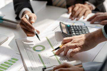 Wall Mural - team of marketing is meeting about company finance, an employee is using calculator to calculate business profit of this year and show to head of department, planning about the best way to work