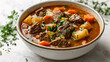 © wasan - Bowl of hearty beef stew with vegetables on a white background