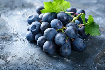 Wall Mural - Closeup of ripe blue grapes with water droplets and green leaves on a dark textured surface