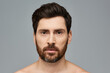 © LIGHTFIELD STUDIOS - A bearded man stands shirtless, exuding confidence and strength.