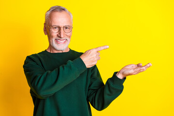 Poster - Photo portrait of handsome retired man point hold empty space wear trendy green outfit isolated on yellow color background