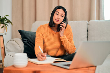 Poster - Woman, laptop and phone call on sofa for remote work, conversation and communication in home. Female person, tech or mobile talking with notebook for contact, review or feedback in living room