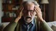 © AS Photo Family - An elderly man with glasses holds his head in pain, depicting a severe headache or moment of stress