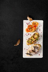 Wall Mural - Gourmet Bruschetta Assortment with Crab, Salmon, Avocado, and Roast Beef on Elegant White Plate