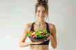 © piai - A happy young slim athletic woman in sportswear with salad bowl. White background, diet concept