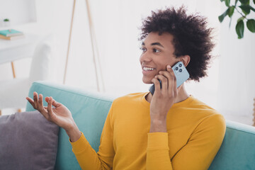 Poster - Portrait of nice young man speak telephone sit sofa wear yellow pullover white interior flat indoors