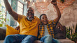 © john - Excited african american father and adult son watching sport on tv and celebrating victory