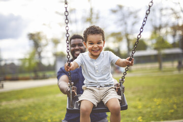 Playtime Moments. father With Her son Swinging Having Fun on the Playground Outside, Sharing Laughter and Joyful Bonding In Park Outdoors