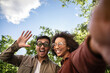 © ADDICTIVE STOCK - Multiethnic couple enjoying outdoor park in Madrid, Spain, smiling and waving